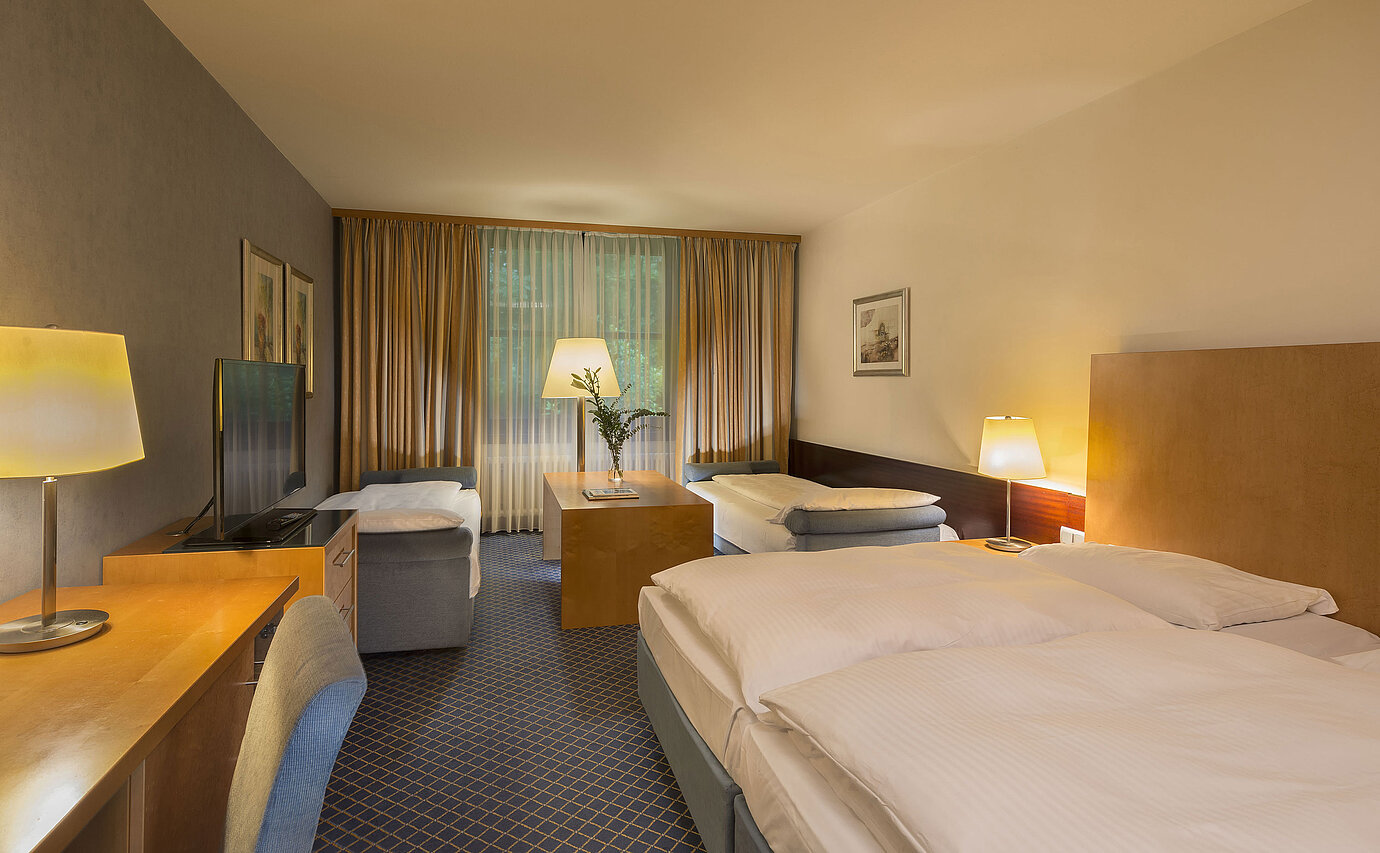 Camera familiare spaziosa al Maritim Hotel Fulda con quattro letti, scrivania e atmosfera accogliente.
