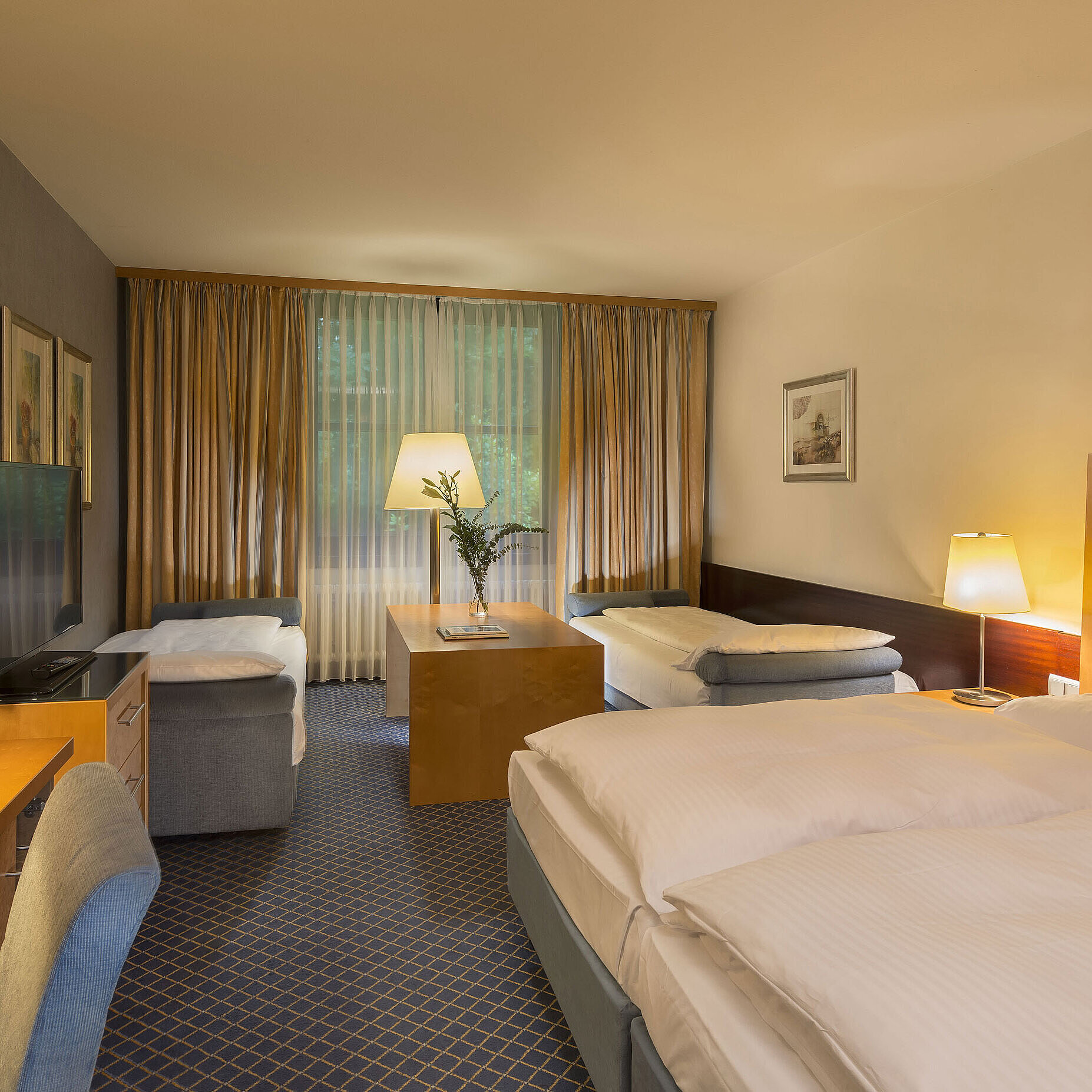 Camera familiare spaziosa al Maritim Hotel Fulda con quattro letti, scrivania e atmosfera accogliente.