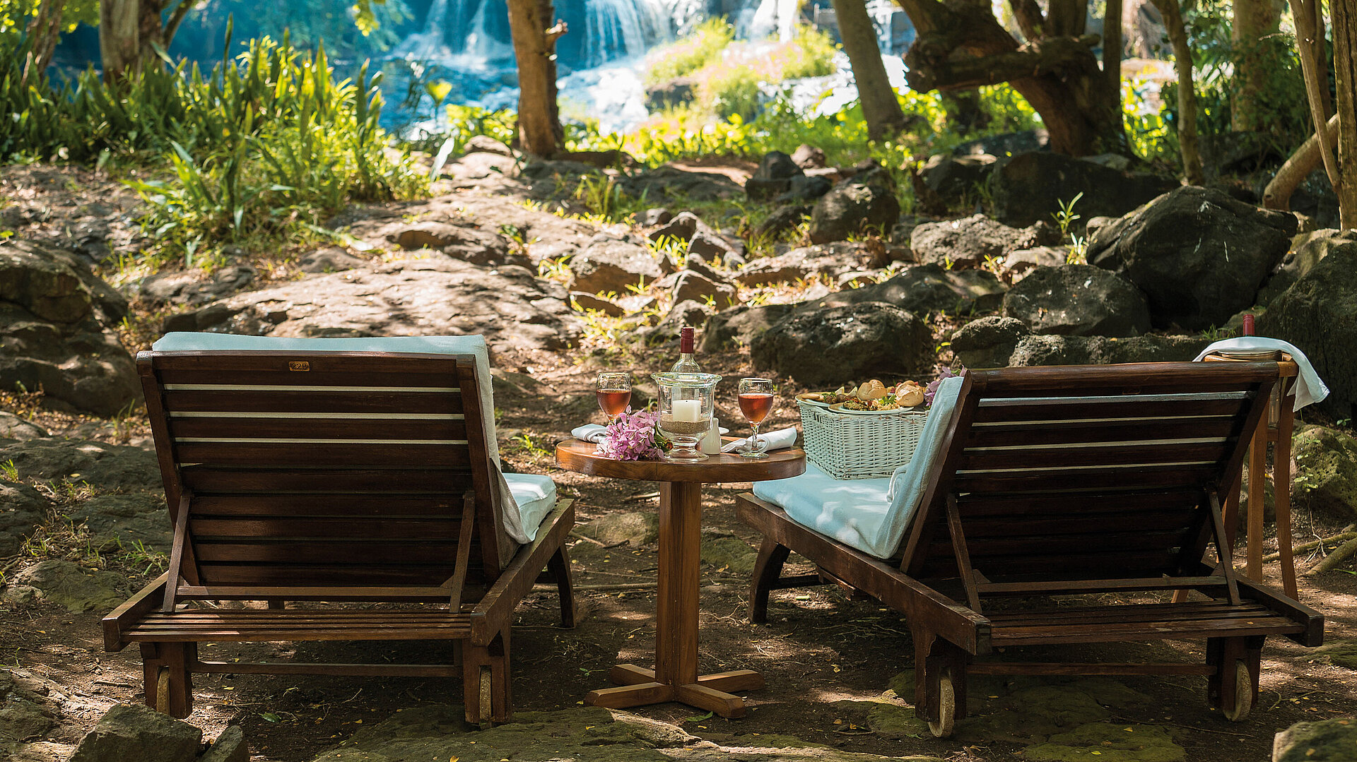 Picnic at the waterfall Two loungers with table in nature overlooking a waterfall for peaceful relaxation