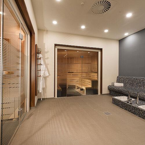 Área de sauna relajante en el Hotel Maritim Bonn con asientos modernos y una pileta Kneipp para recuperación y bienestar.