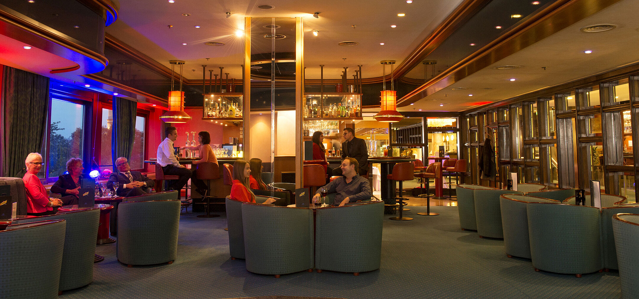 Huéspedes disfrutan de bebidas y charla en el bar del Maritim Hotel Travemünde por la noche