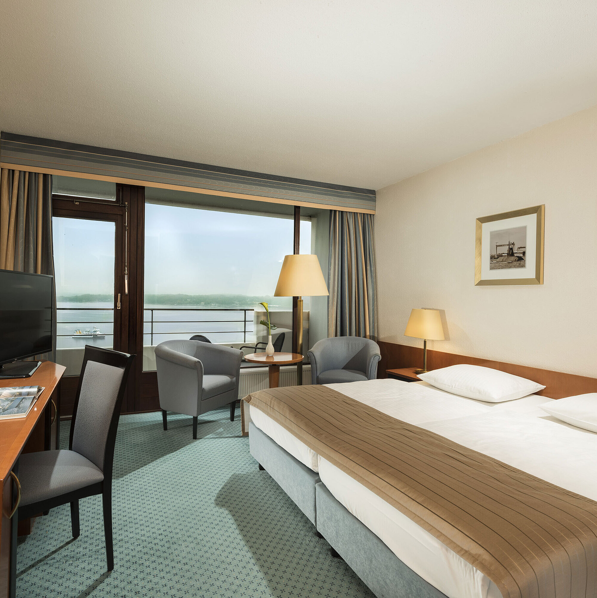Habitación Superior Habitación superior del Maritim Hotel Kiel con escritorio, zona de estar, cama doble grande y balcón con vistas al fiordo.
