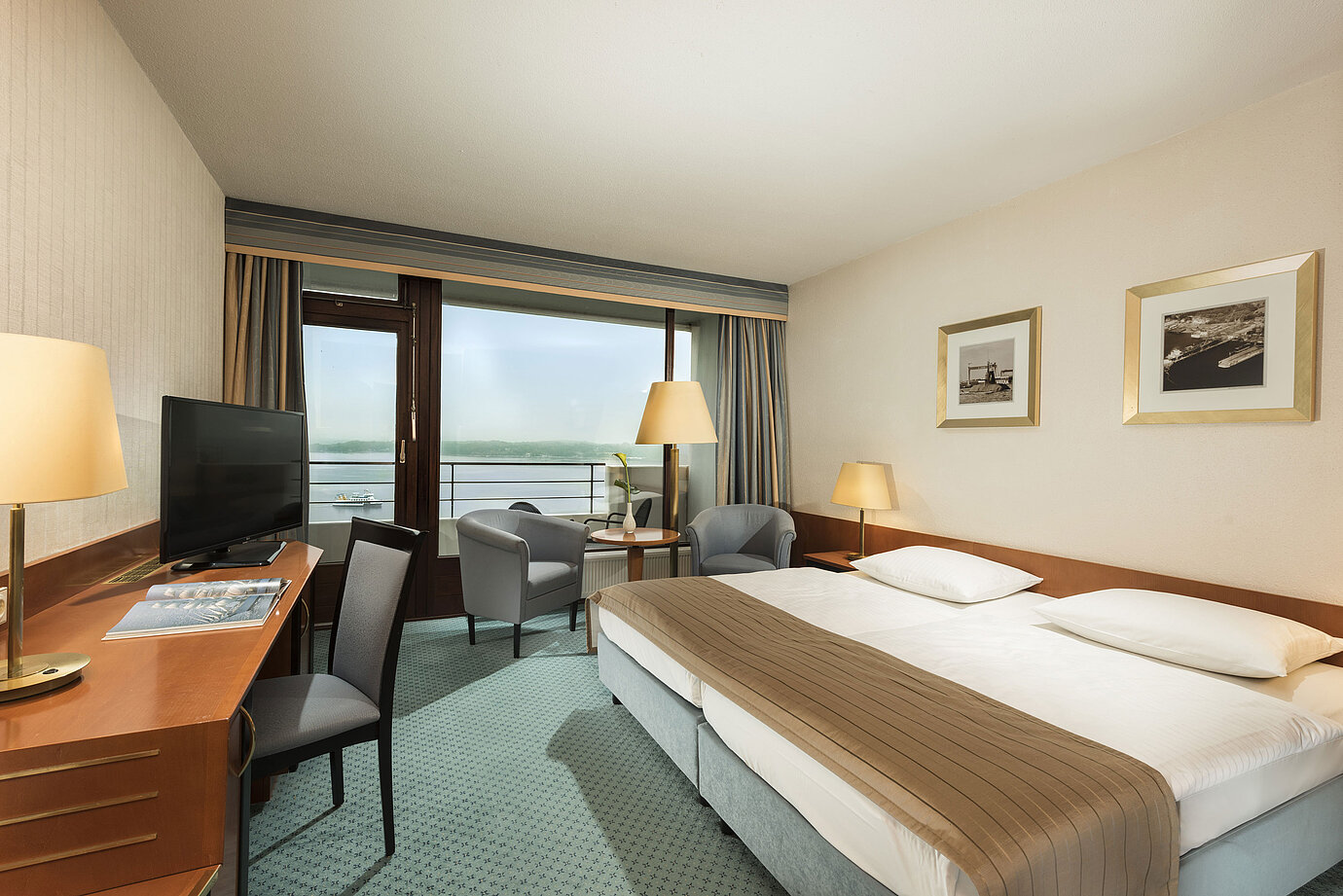 Chambre supérieure au Maritim Hotel Kiel avec bureau, coin salon, grand lit double et balcon avec vue sur le fjord.