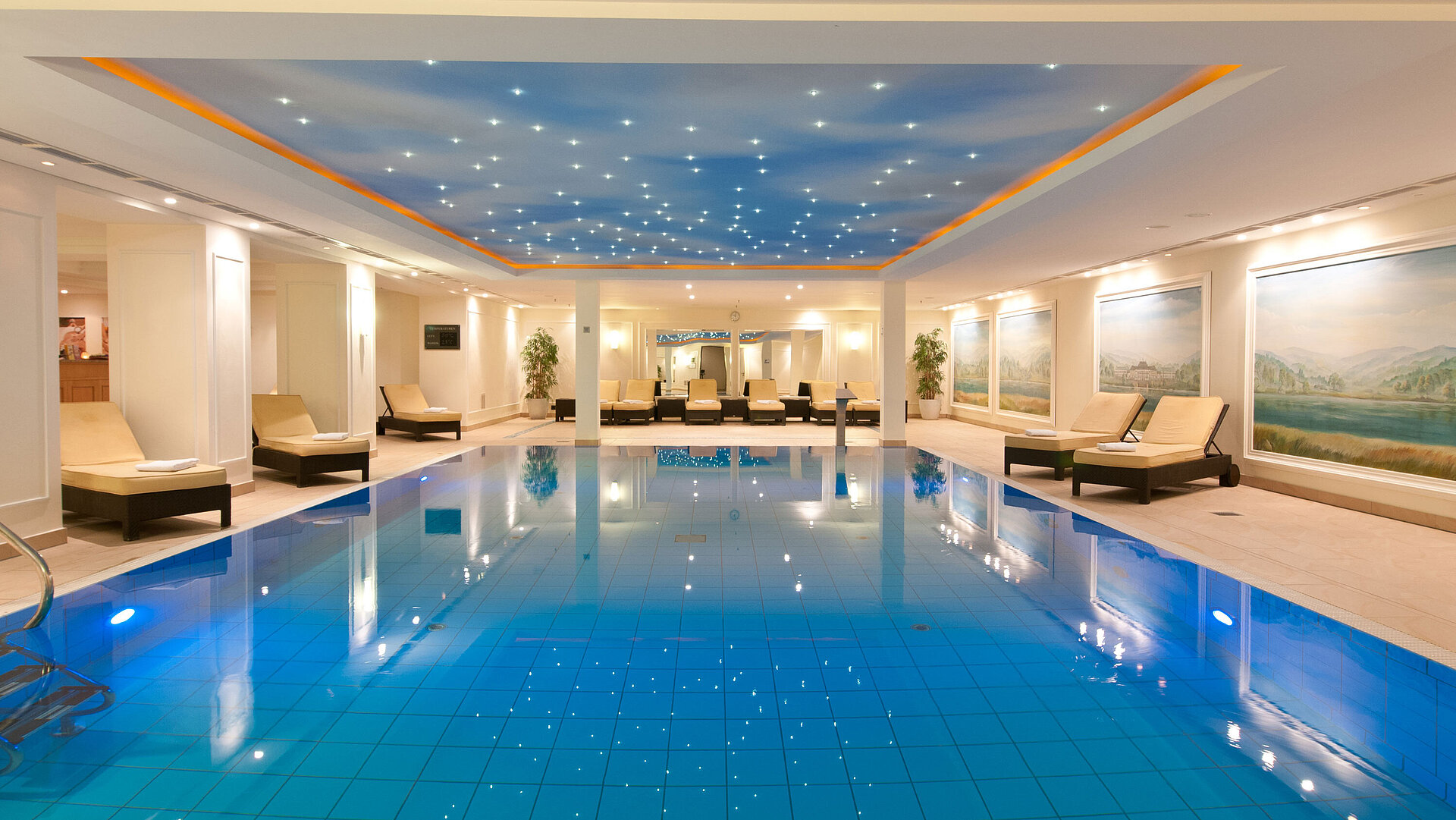 Luxurious indoor pool at the Maritim Hotel Dresden with loungers and atmospheric ceiling lighting.