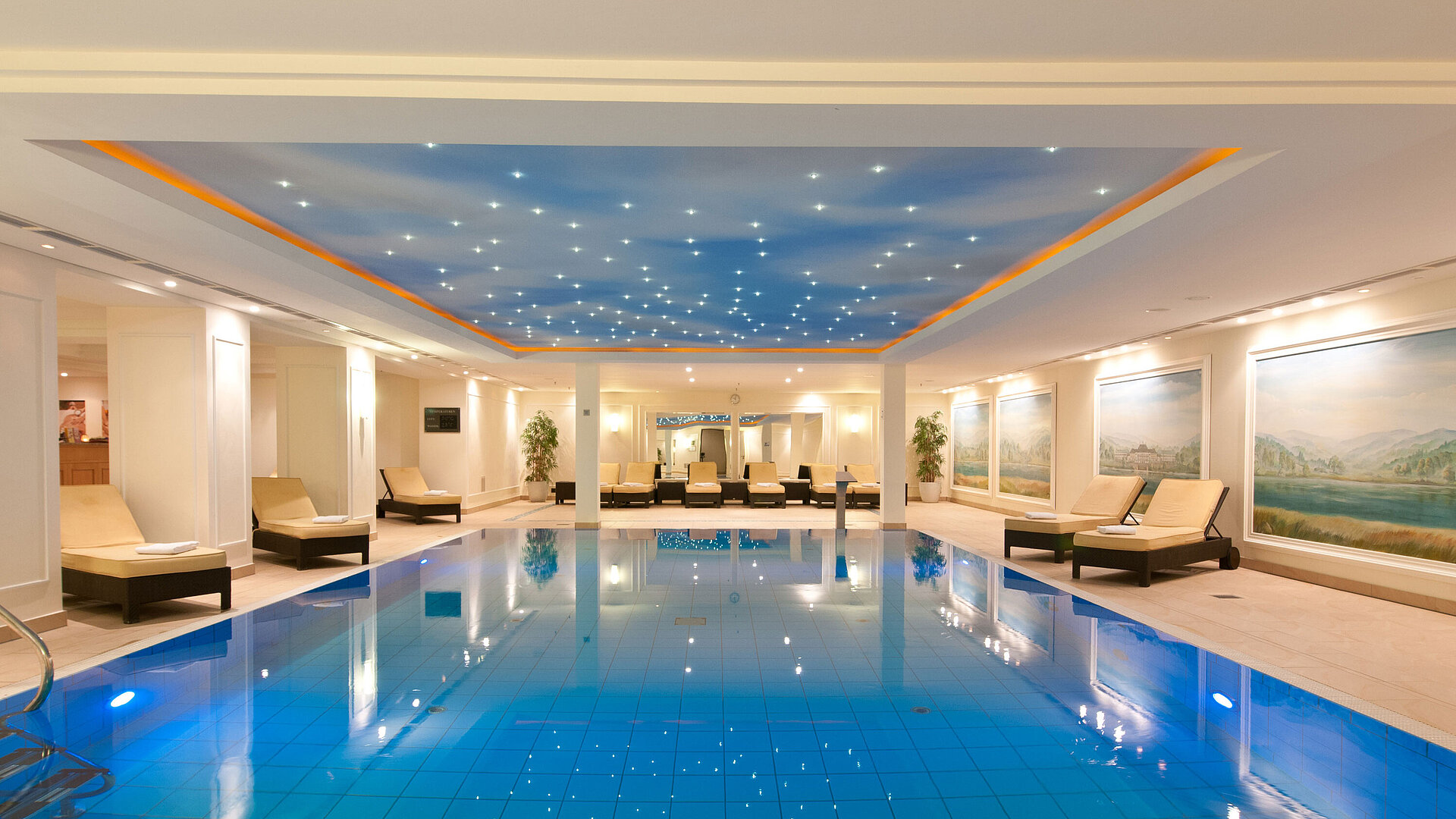 Piscina coperta lussuosa al Maritim Hotel Dresden con lettini e illuminazione suggestiva sul soffitto.