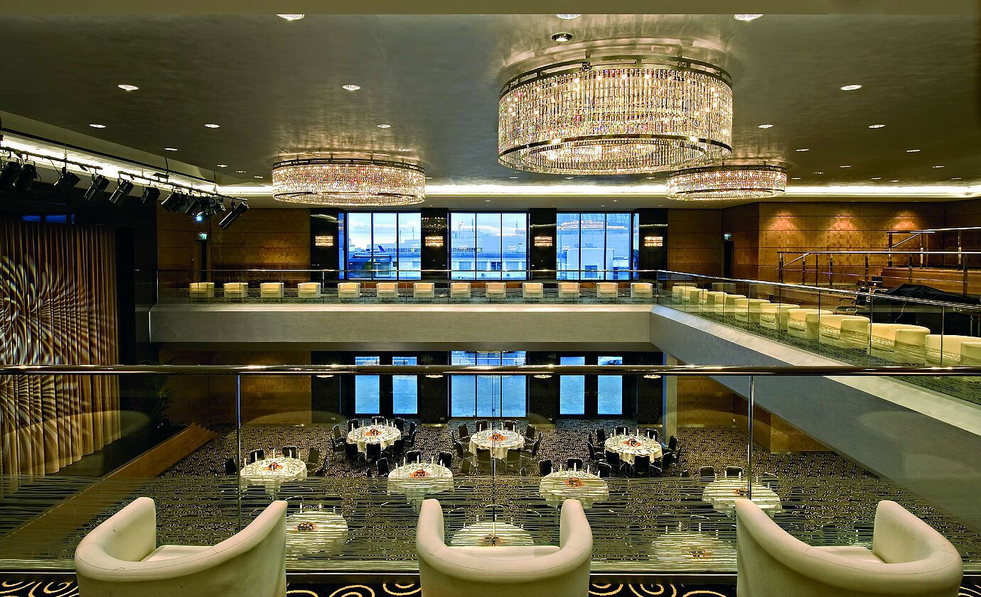 Elegante salón en el Maritim Hotel Düsseldorf con impresionantes lámparas de araña, arquitectura moderna y un gran escenario.