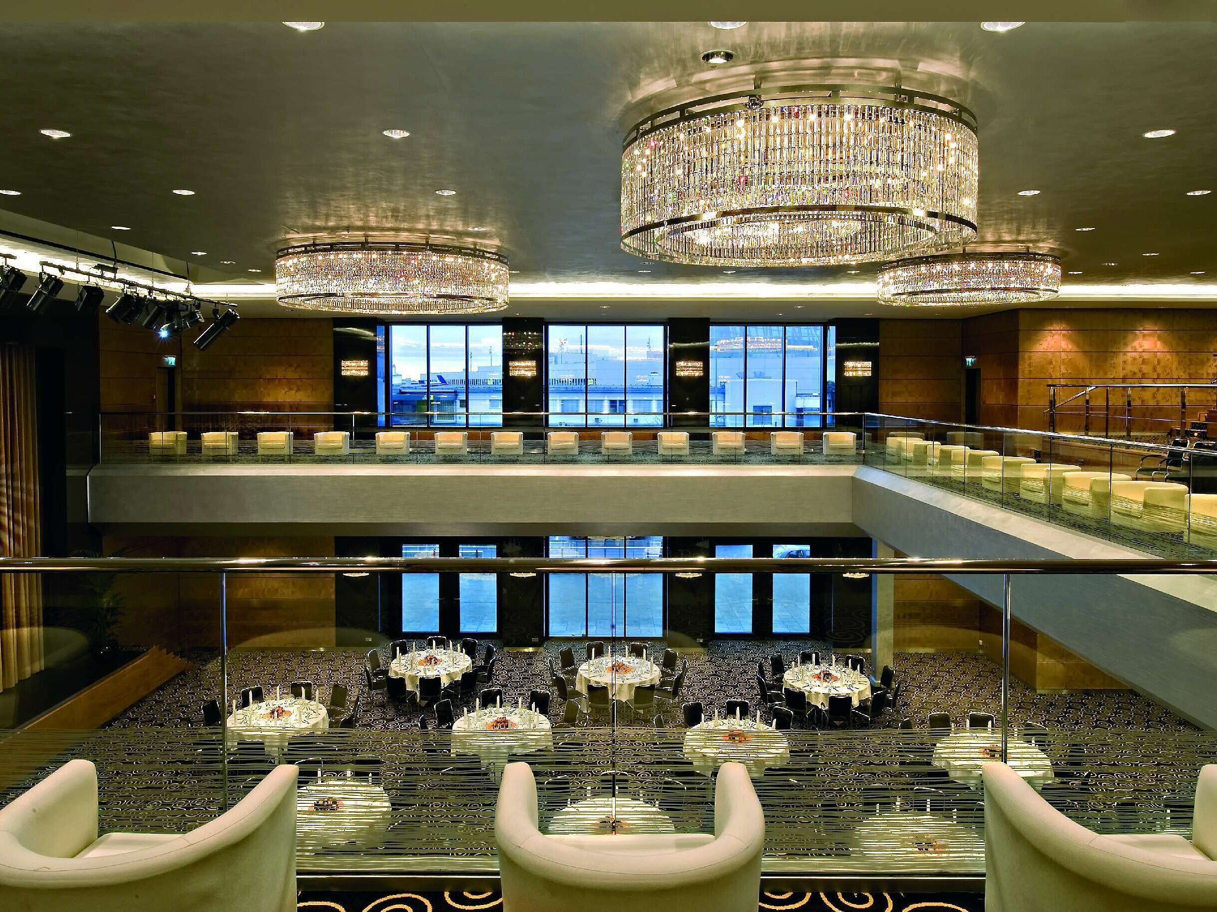 Elegante salón en el Maritim Hotel Düsseldorf con impresionantes lámparas de araña, arquitectura moderna y un gran escenario.