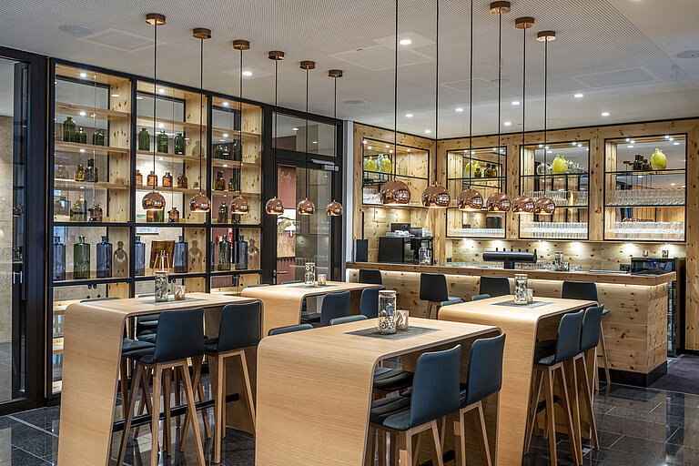Bar élégante avec décoration en bois, luminaires suspendus stylés et sièges hauts au Maritim Hotel Ingolstadt.
