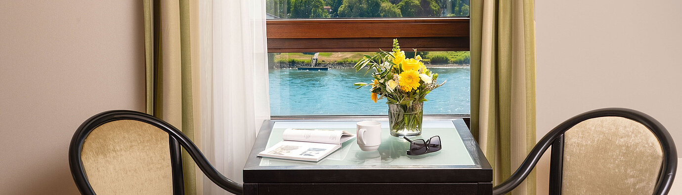 Junior Suite Table and seating by the window in the Junior Suite at Maritim Hotel Königswinter overlooking the River Rhine.