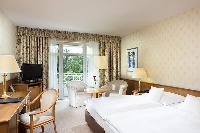 Bright double room with balcony view and seating area at Maritim Hotel Bad Wildungen