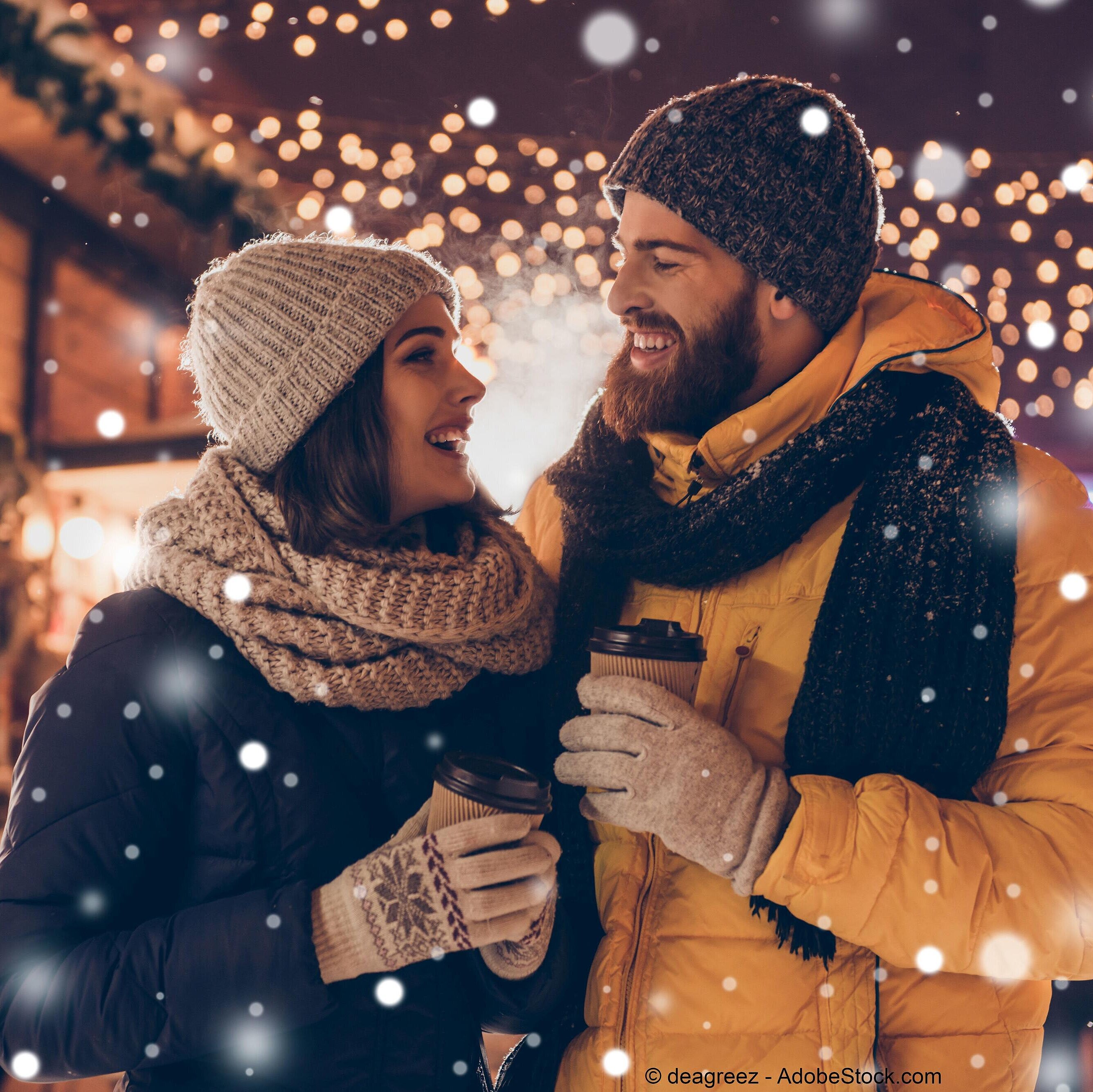 Couple enjoying hot drinks at a wintry Christmas market