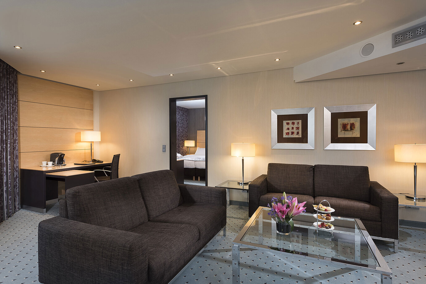 Junior Suite en el Maritim Hotel Düsseldorf con área de estar separada, dos sofás, escritorio, flores y diseño moderno.
