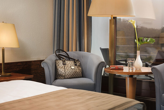 Chambre Classic du Maritim Hotel Kiel avec un coin salon confortable, une lampe de table et une décoration élégante, idéale pour les moments de détente.