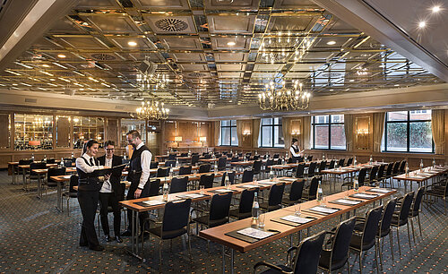 Dos empleados preparan sala de reuniones con sillas en fila en el Maritim Hotel Stuttgart