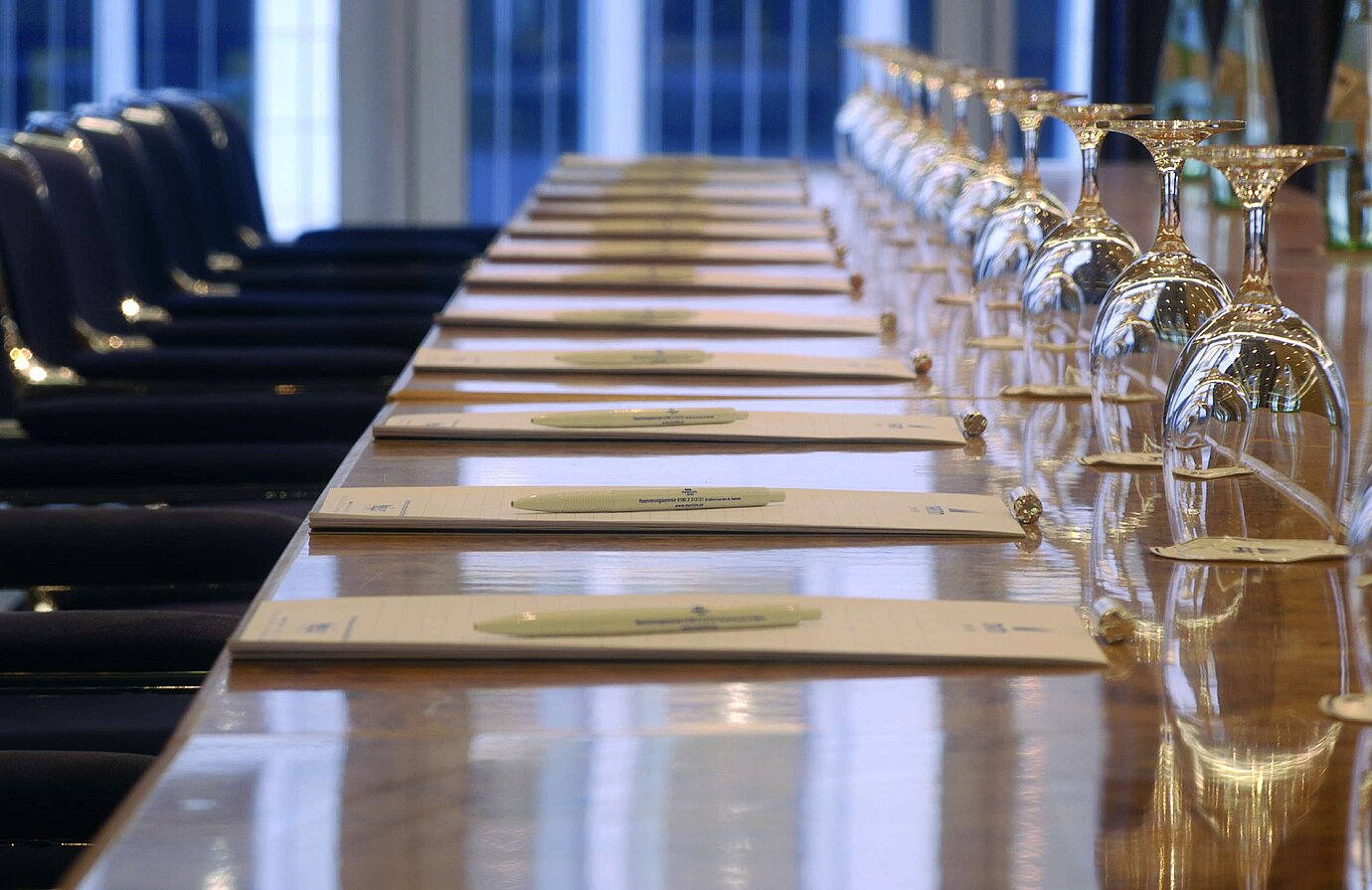 Gros plan d'une table de conférence préparée à l'hôtel Maritim proArte Berlin, avec des carnets et des verres à vin.