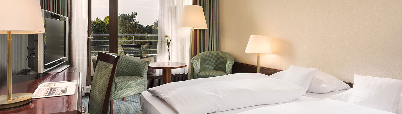 Habitación con balcón, escritorio y sillones en Maritim Hotel Bad Salzuflen