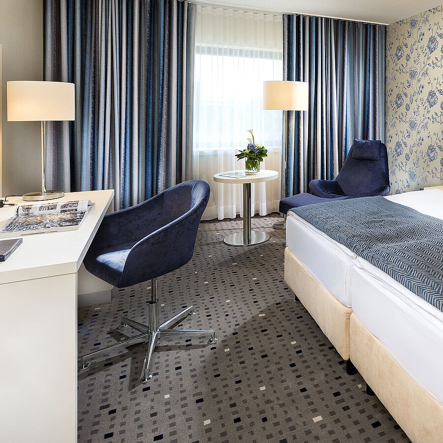 Chambre supérieure à l'hôtel Maritim Bonn avec un design moderne, lit confortable, bureau et rideaux élégants.