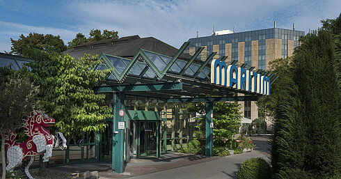 Main entrance of Maritim Hotel Stuttgart with glass roof, green facade and Maritim logo