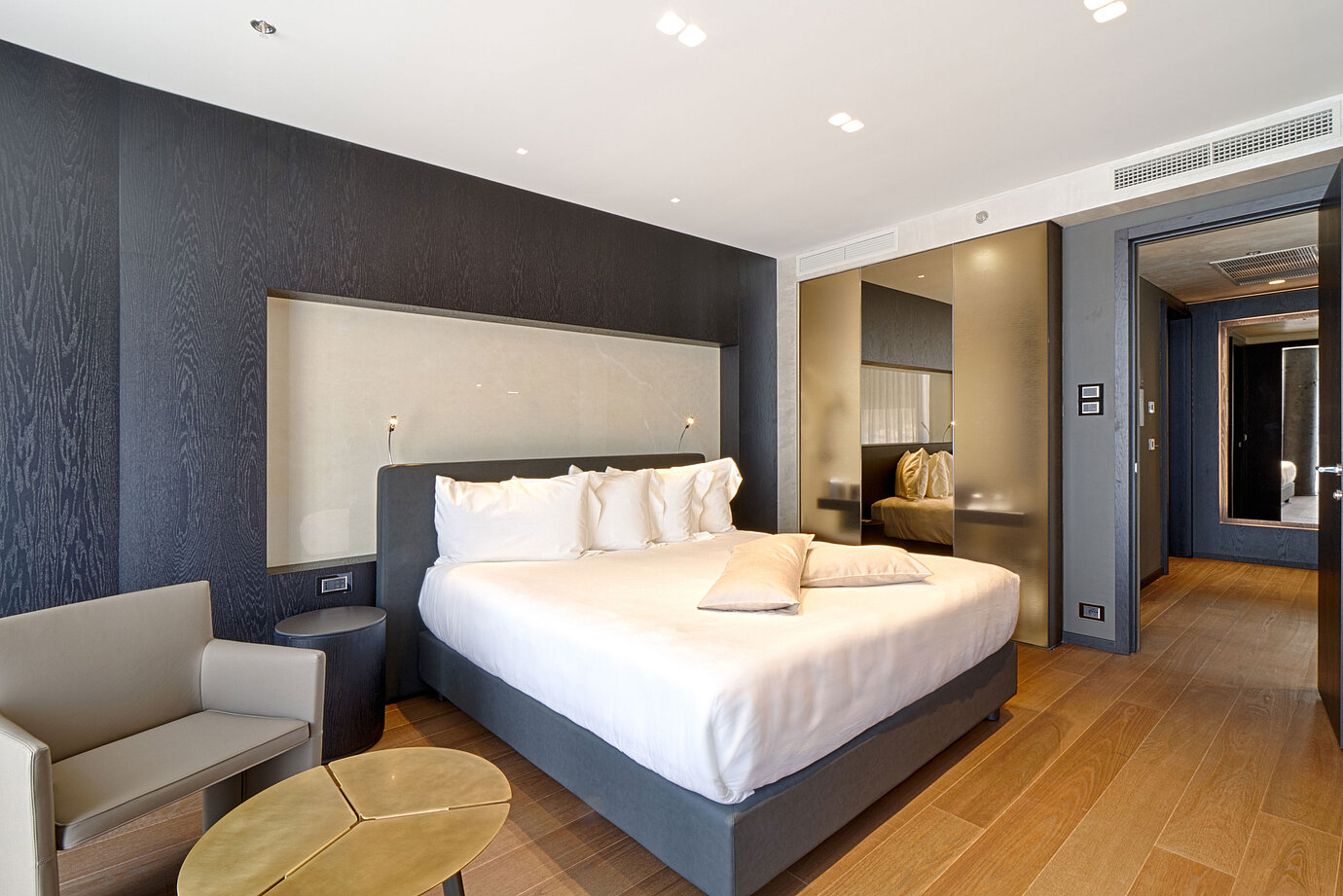 Modern hotel room with king-size bed, light wall niche and wooden floor at Maritim Hotel Plaza Tirana