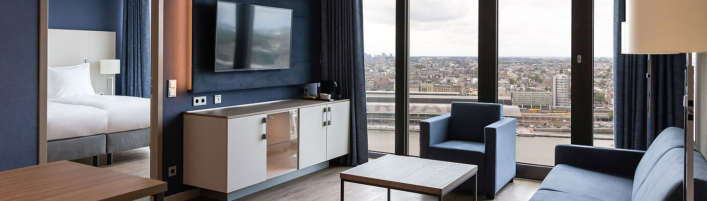 Soggiorno moderno con vista città e TV al Maritim Hotel Amsterdam