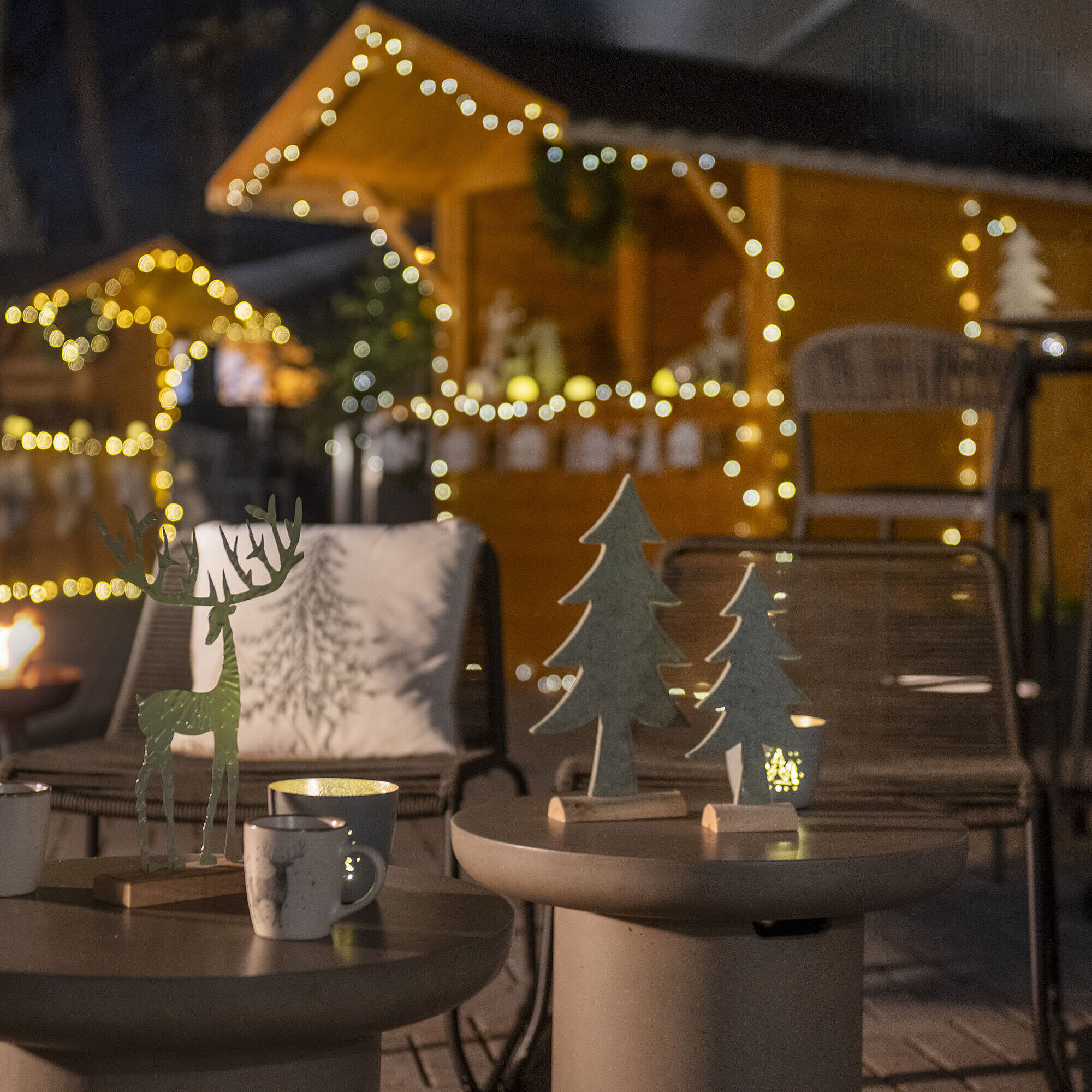 Festively decorated outdoor area of Maritim Hotel Darmstadt with fairy lights, wooden decorations, and a fire bowl.