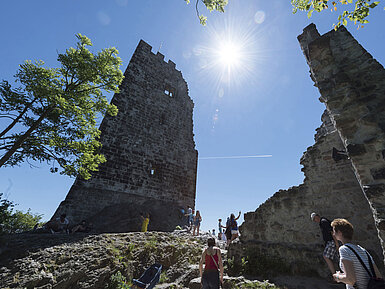 The historic Drachenfels castle ruins in Königswinter with visitors and bright sunshine.