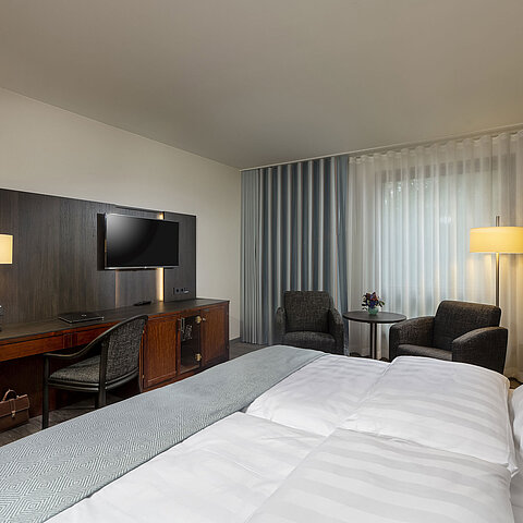 Elegant double room at Maritim Hotel Bremen with modern furnishings, comfortable beds, and a cozy seating area.