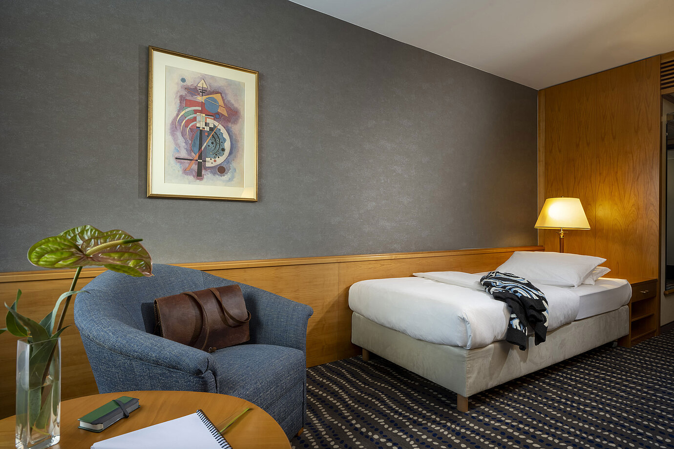 Classic single room with desk, bedside lamp, and modern wall art
