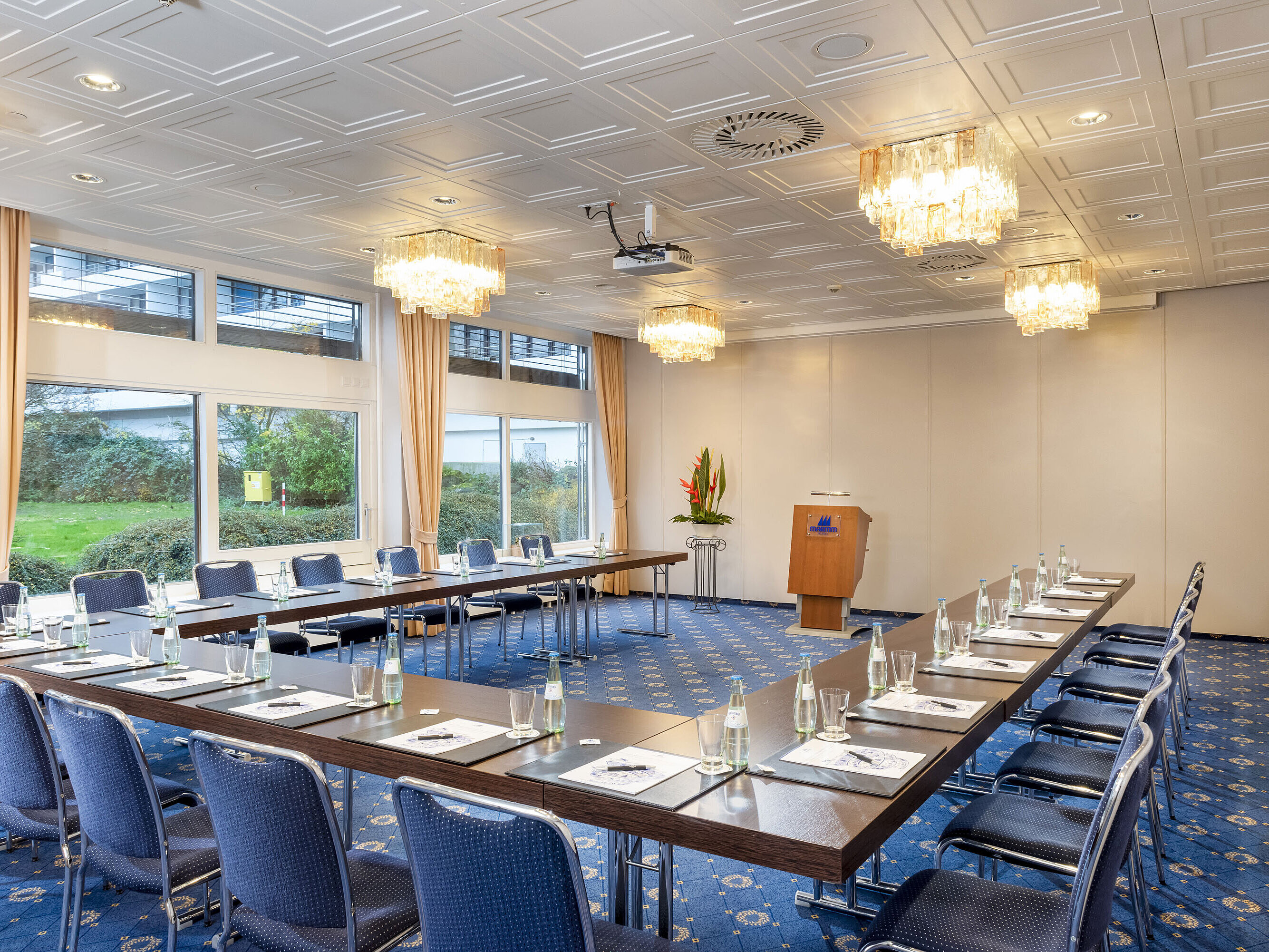 El Salón Lübeck del Maritim Hotel Kiel, una moderna sala de conferencias con asientos en forma de U, grandes ventanales y lámparas de araña.