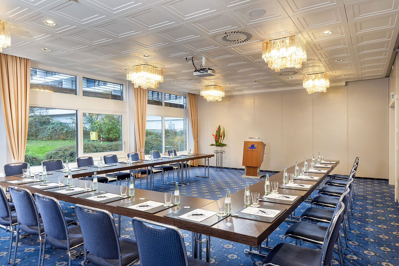 Il Salon Lübeck del Maritim Hotel Kiel, una moderna sala conferenze con sedute a U, grandi finestre e lampadari.