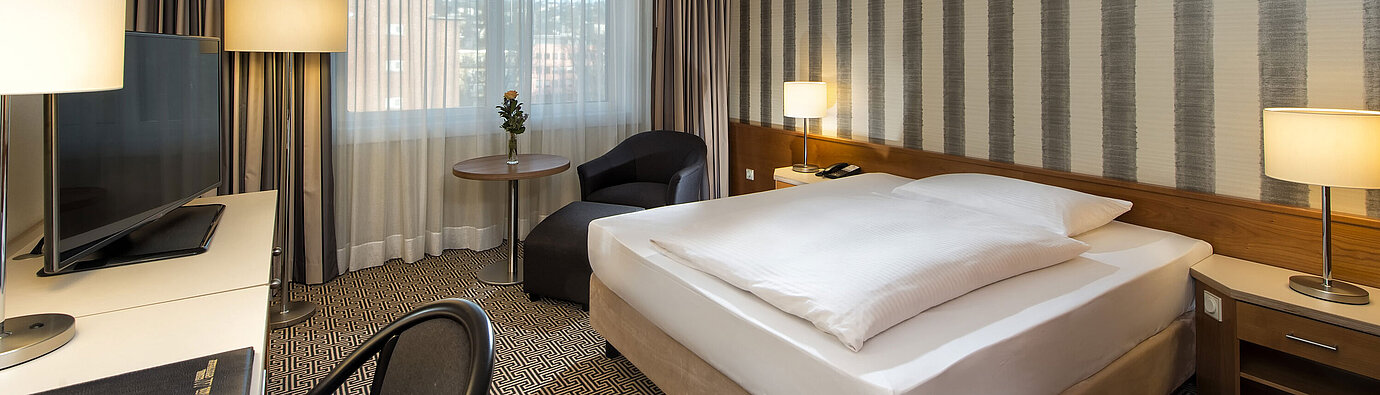 Modern single room with desk, large window and city view at Maritim Hotel Stuttgart