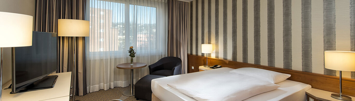 Modern single room with desk, large window and city view at Maritim Hotel Stuttgart