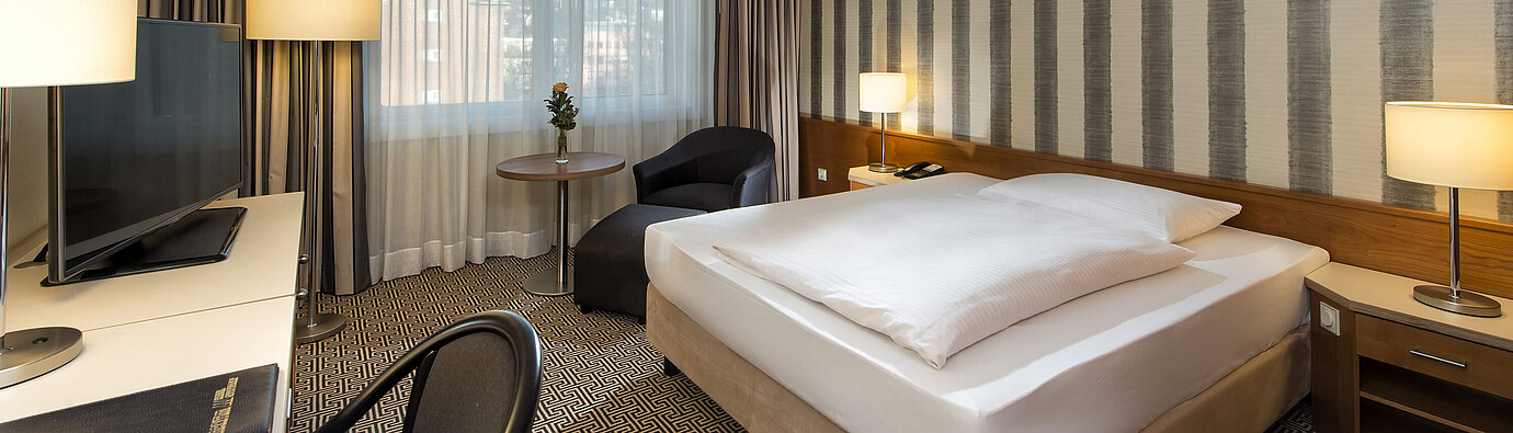 Modern single room with desk, large window and city view at Maritim Hotel Stuttgart