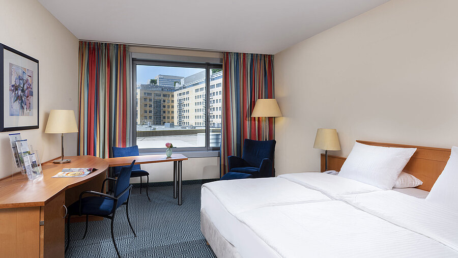 Camera Classic del Maritim Hotel Frankfurt con letto matrimoniale, scrivania e vista sulla città.