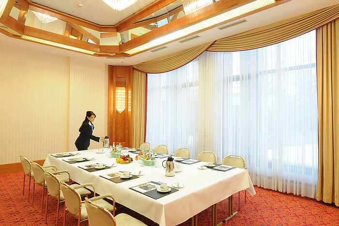 Salle de réunion élégante avec lumière naturelle, table dressée et ambiance chaleureuse au Maritim Hotel Magdeburg.