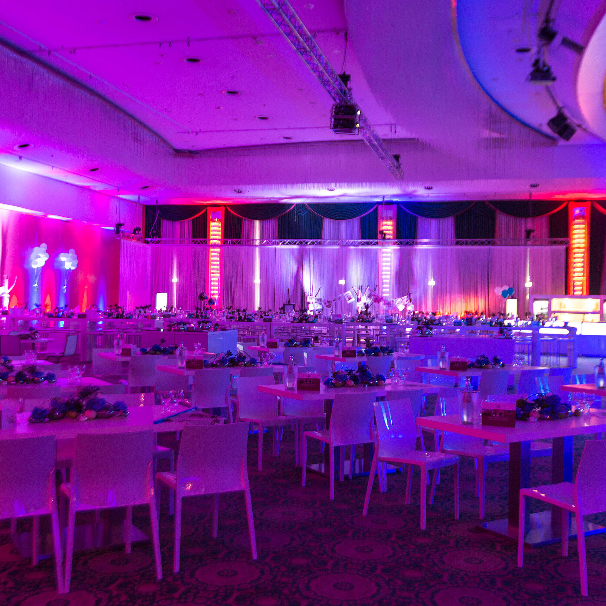 An elegant event venue at Maritim Hotel with festively set tables and atmospheric lighting for events.