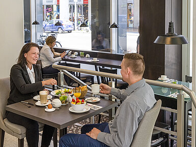 Ospiti che gustano una ricca colazione all'hotel Maritim Berlin, circondati da un arredamento moderno e grandi finestre.