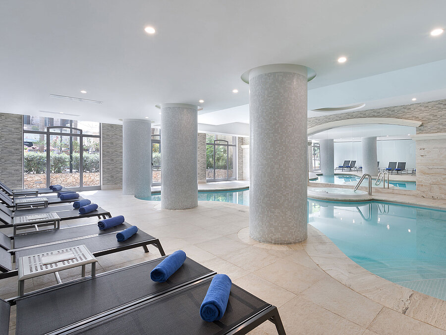 Piscina coperta Moderna piscina coperta con lettini e asciugamani nella spa del Maritim Antonine Hotel & Spa Malta per piacevoli momenti di relax e benessere.