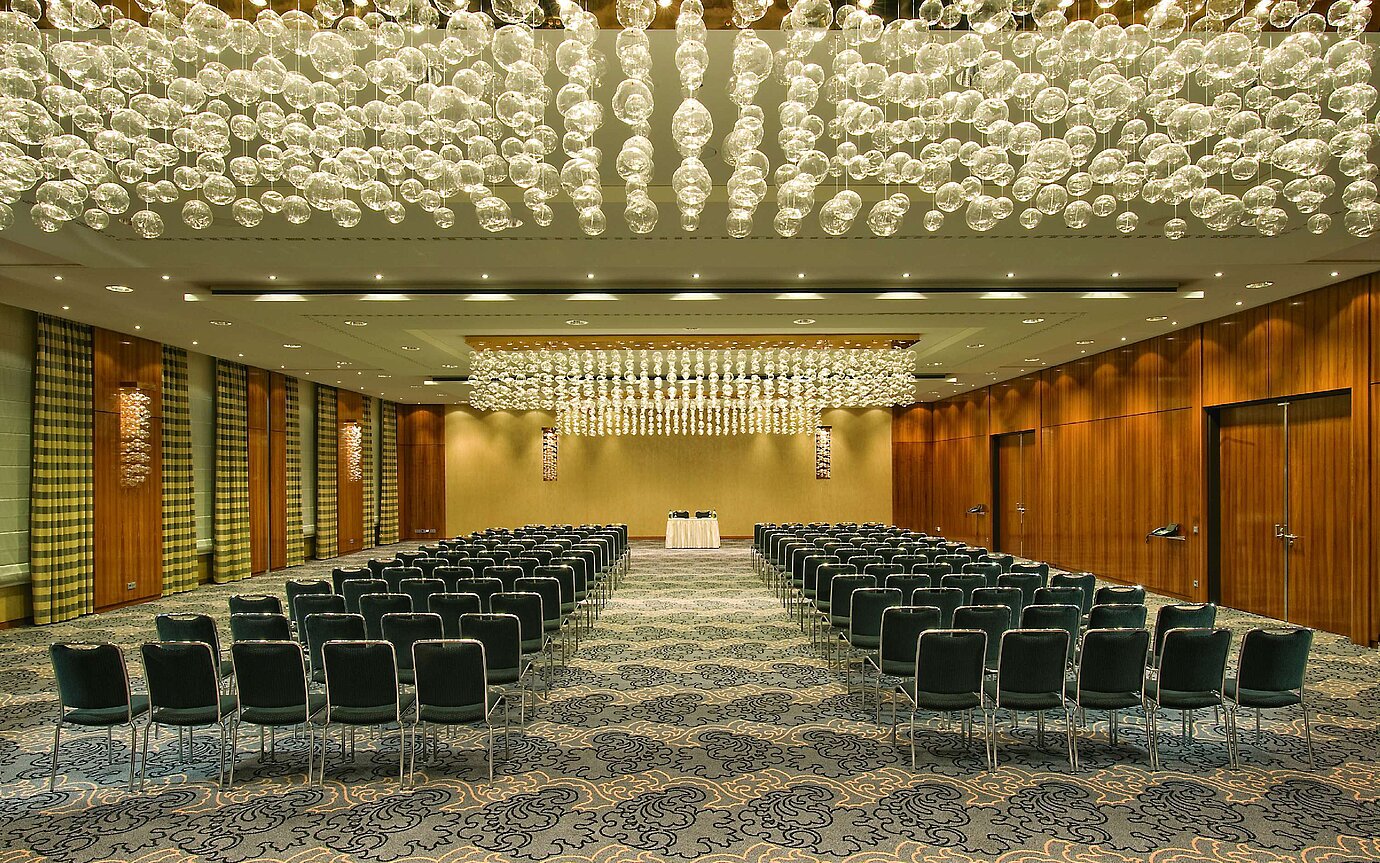 Sala elegante de eventos en el Maritim Hotel Düsseldorf con iluminación artística y asientos en fila, ideal para eventos.