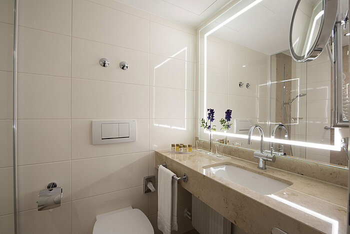 Bagno luminoso con grande specchio e prodotti al Maritim Hotel Titisee