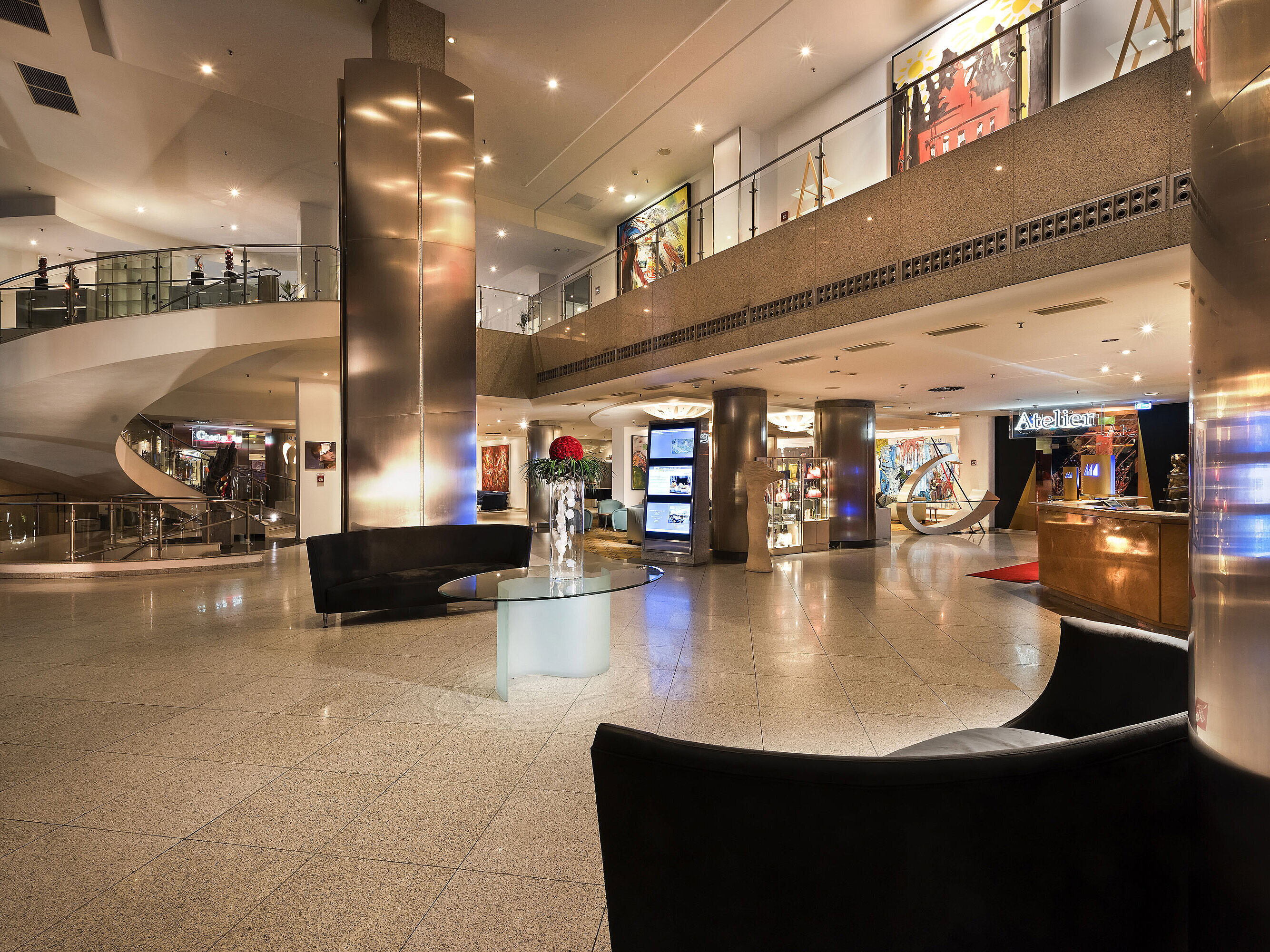 Elegante hall con opere d'arte moderne e scala curva al Maritim proArte Hotel Berlino.