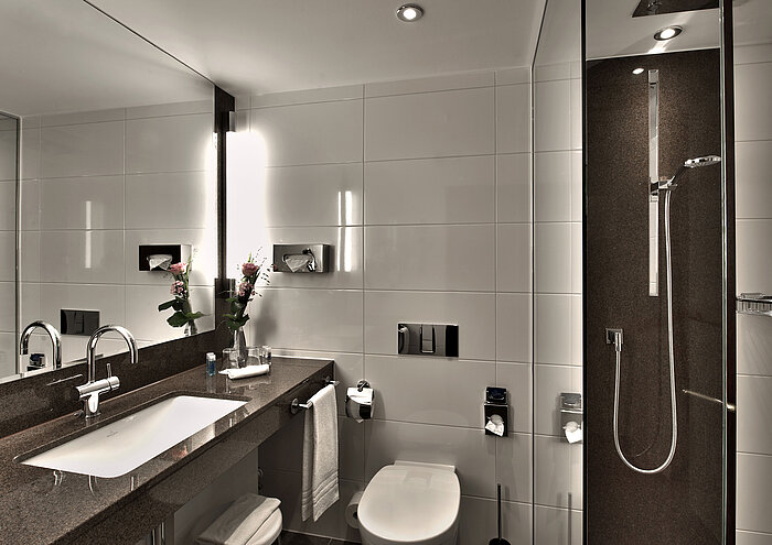 Baño moderno en el Maritim Hotel Colonia con bañera, gran espejo y elegante iluminación en tonos neutros.