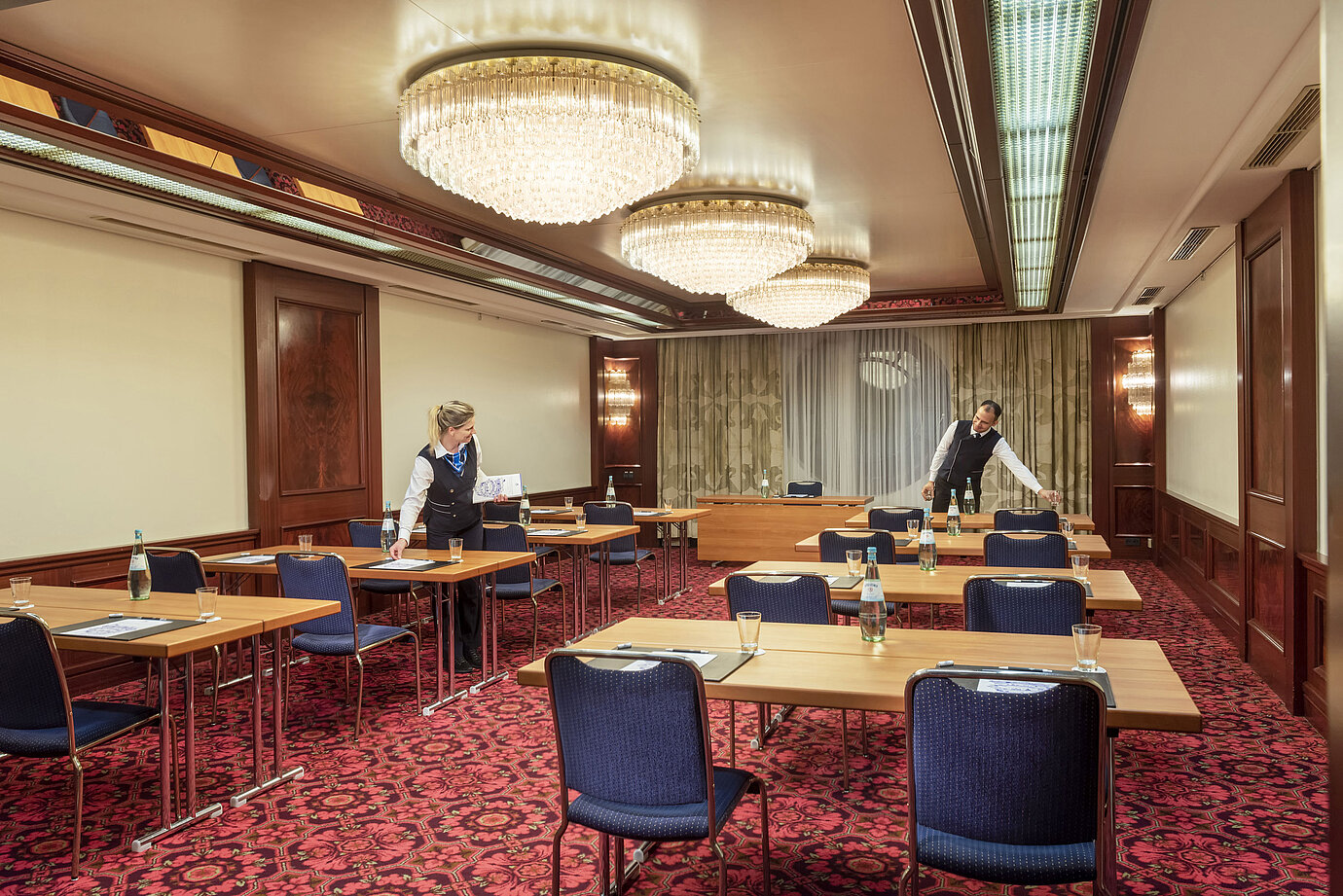 Salón Bonn en Maritim Colonia, el personal prepara la sala con mesas, botellas de agua y vasos para un evento.