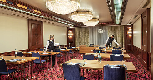 Salon Bonn at Maritim Cologne, staff preparing the room with tables, water bottles, and glasses for an event.
