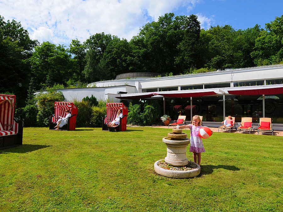 Giardino del Maritim Hotel Bad Wildungen con sedie da spiaggia, lettini e area giochi