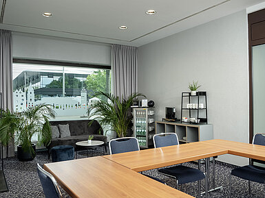 Salon Kiel con sofá, plantas y gran ventanal en el Maritim Hotel Darmstadt