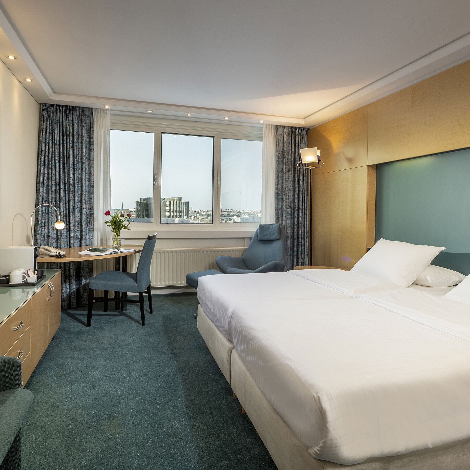 Camera Superior arredata in stile moderno presso l'hotel Maritim con letto grande,scrivania, opera d'arte e vista sulla città