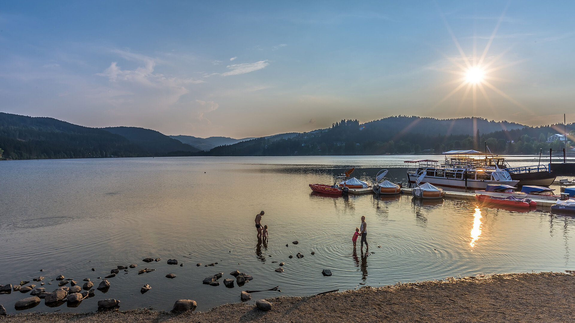 Sunset at Lake Titisee with swimmers and boats near the Maritim Hotel Titisee