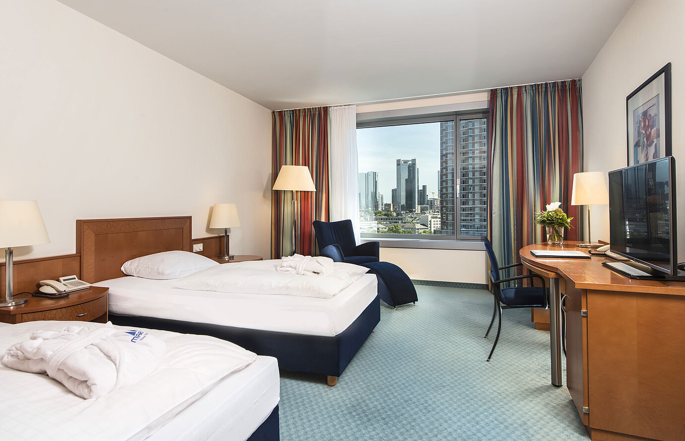Chambre supérieure à l'hôtel Maritim Frankfurt avec deux lits simples, bureau, coin salon et vue imprenable sur la skyline.