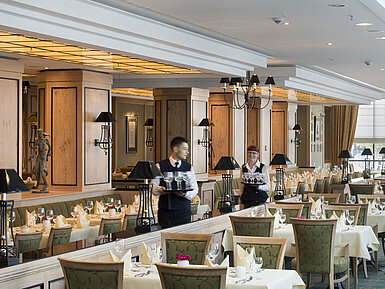Restaurant 'Wintergarten' à l'hôtel Maritim de Dresde avec tables dressées et personnel accueillant.